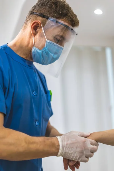 按摩师一种理疗师 带着屏风和面罩给病人做腕部按摩对Coronavirus大流行病Covid 19采取保护措施的理疗 治疗性脊椎按摩 — 图库照片