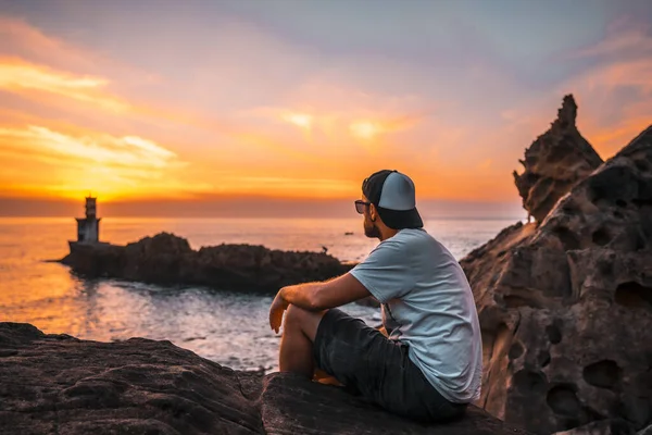 Ein Junger Mann Sitzt Auf Einem Felsen Und Beobachtet Den — Stockfoto