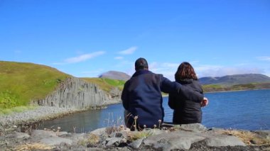 Olafsfjordur sahilindeki güzel taş duvarları izleyen mutlu çift. İzlanda