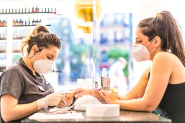 Manikür ve pedikür güzellik salonu güvenlik önlemleri ve maskeli insanlar pedikür yapıyor. Korod-19 salgınından sonra tekrar açılıyor. Coronavirüs