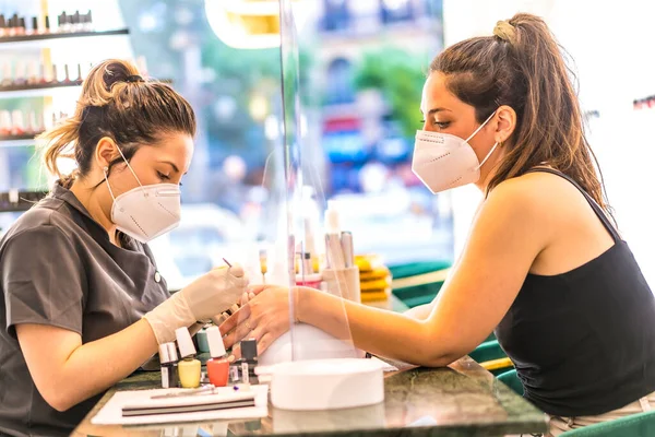 A worker with security measures working with a client. Reopening after the coronavirus pandemic. Manicure and Pedicure Salon.