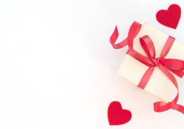 Kırmızı kurdeleli, beyaz arka planda, iki kırmızı kalpli beyaz hediye kutusu. Sevgililer Günü konsepti. Sevgililer Günü tebrik kartı. Düzleştirme biçimi.