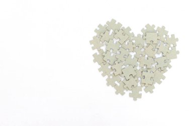 Beyaz arka planda bulmacalardan yapılmış bir kalp. Sevgililer Günü tebrik kartı. Sevgililer Günü, aşk, mutluluk ve düğün konsepti. Kopya alanı ile düz uzanma biçimi.