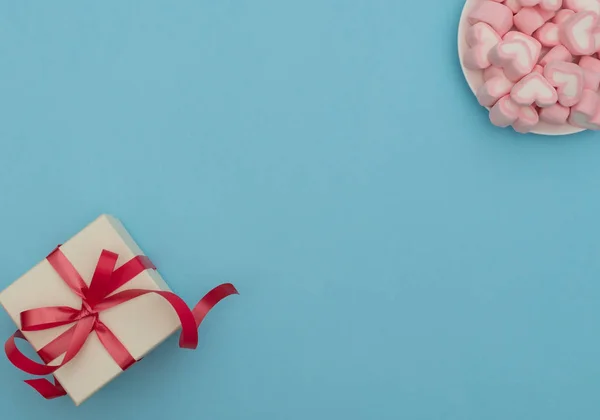 情人节的概念 白色礼品盒 红色缎带 心形棉花糖 蓝底白色碗 情人节贺卡 具有复制空间的平面布局风格 — 图库照片