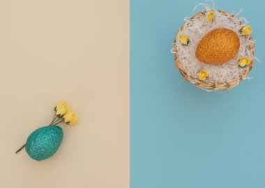 Colored orange Easter egg in egg basket with white paper like a nest and blue egg with yellow spring flowers lie on double coloured blue and beige background. Happy Easter holiday. Flat lay style.