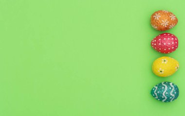 Renkli turuncu, mavi, kırmızı ve sarı paskalya yumurtaları yeşil arka planda. Mutlu Paskalya tatili konsepti. Kopya alanı ile düz uzanma biçimi