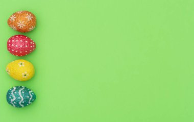 Renkli turuncu, mavi, kırmızı ve sarı paskalya yumurtaları yeşil arka planda. Mutlu Paskalya tatili konsepti. Kopya alanı ile düz uzanma biçimi
