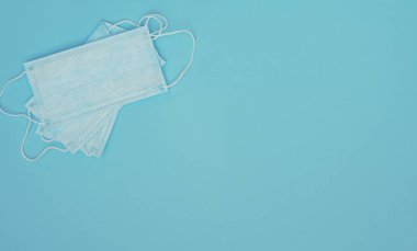 Mavi arka planda açık mavi tıbbi maskeler. Mevsimsel hastalıklar. Tıp konsepti. Fotokopi alanı ve üst görünümü olan düz konum biçimi.