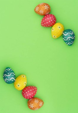 Renkli turuncu, mavi, kırmızı ve sarı paskalya yumurtaları yeşil arka planda. Mutlu Paskalya tatili konsepti. Kopya alanı ile düz uzanma biçimi.
