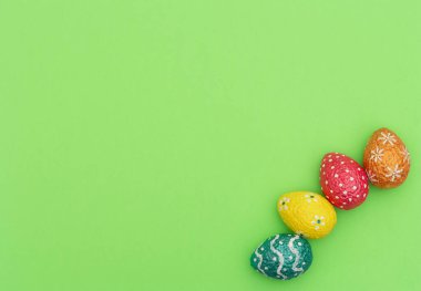 Renkli turuncu, mavi, kırmızı ve sarı paskalya yumurtaları yeşil arka planda. Mutlu Paskalya tatili konsepti. Kopya alanı ile düz uzanma biçimi.