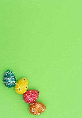 Renkli turuncu, mavi, kırmızı ve sarı paskalya yumurtaları yeşil arka planda. Mutlu Paskalya tatili konsepti. Kopya alanı ile düz uzanma biçimi.