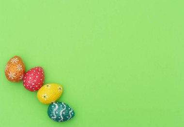 Renkli turuncu, mavi, kırmızı ve sarı paskalya yumurtaları yeşil arka planda. Mutlu Paskalya tatili konsepti. Kopya alanı ile düz uzanma biçimi.