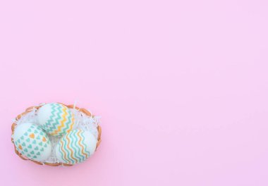 Süslü Paskalya yumurtaları pembe arka planda sepette yatıyor. Mutlu Paskalya tatili konsepti. Selamlar, davetiye. Kopya alanı ile düz uzanma biçimi.
