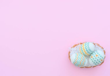 Süslü Paskalya yumurtaları pembe arka planda sepette yatıyor. Mutlu Paskalya tatili konsepti. Selamlar, davetiye. Kopya alanı ile düz uzanma biçimi.