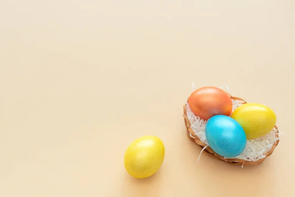 Decorated Easter eggs lie in the basket like a nest on yellow background. Happy Easter holiday concept. Greeting, invitation card. Flat lay style with copy space.