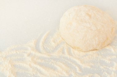 Gri zemin üzerinde buğday unuyla kaplanmış taze çiğ hamur topu ve un tozu. Ev yemeği, evde kalmak, konsept pişirmek. Metin için alanı kopyala. 