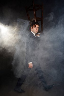 Siyah bir takım elbise, bir erkekte taşır sandalye.