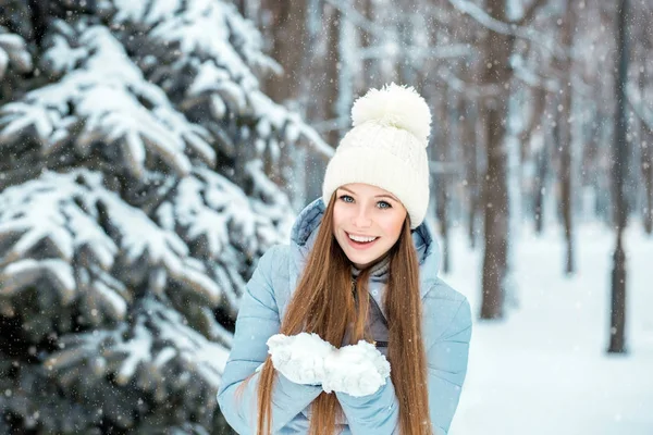 Bir kız sıcak kış giysileri ve bir kış ormanda poz bir şapka giymiş. Noel ağacının yakınında güzel bir gülümseme ile model.