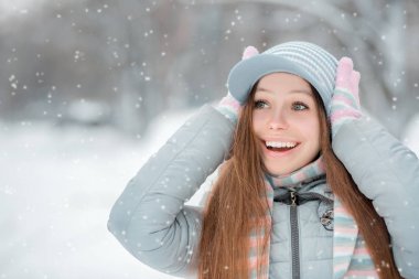 Genç güzel mutlu gülümseyen kız açık yakın çekim portresi, şık giyim kış şapka ve eldiven örme. Modeli ifade joy, gün ışığı. Kafasına iki eliyle tutarak ve th için arıyorsunuz