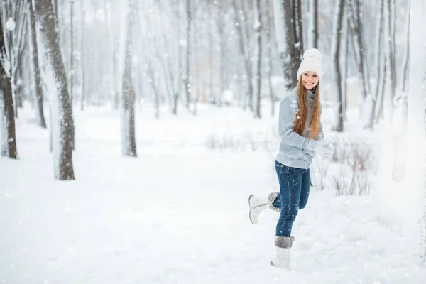 Ritratto da primo piano all'aperto di giovane bella ragazza felice sorridente, indossando eleganti cappelli e guanti invernali in maglia. Una ragazza che corre attraverso la foresta innevata . — Foto Stock