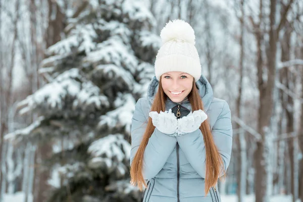 Ritratto da primo piano all'aperto di giovane bella ragazza felice sorridente, indossando eleganti cappelli e guanti invernali in maglia. Modello che esprime gioia Luce del giorno. Effetto nevicata magico. Tonica — Foto Stock