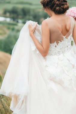 Doğada düğün elbise gelin arkasında. Vücut parçaları, yakın çekim portre.