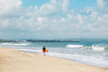 genç bir adam onun surfboard ile plaj boyunca yürüyüş.