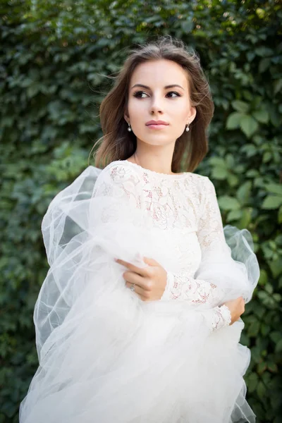 Menina de vestido branco e véu posando contra fundo verde — Fotografia de Stock