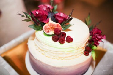 İncir ve yeşil biberiye ile dekore edilmiş rustik düğün pastası.