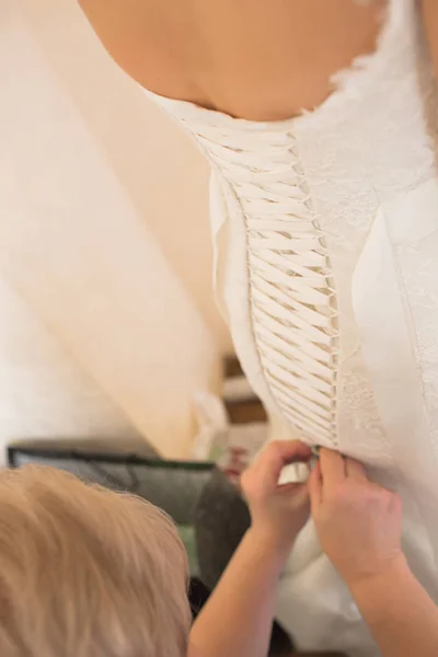 Lace-up wedding dress, rear view. The bride is helped to dress and lace the wedding dress. — Stock Photo, Image