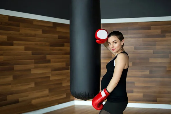 Deportes y fitness para mujeres embarazadas. Joven mujer embarazada hermosa en el gimnasio de fitness. Joven mujer embarazada hermosa en el gimnasio con guantes de boxeo . —  Fotos de Stock