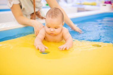 Sağlık prosedürleri sırasında havuzda yüzen küçük bir bebek..