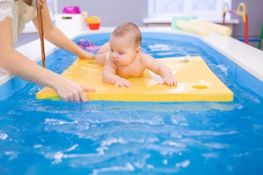 Sağlık prosedürleri sırasında havuzda yüzen küçük bir bebek..