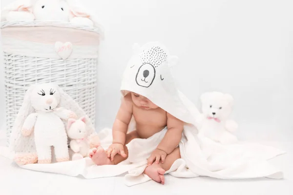 Cute baby under a white towel with a hood after a bath. Baby in a towel. Children's portrait. Healthcare concept. — Stock Photo, Image