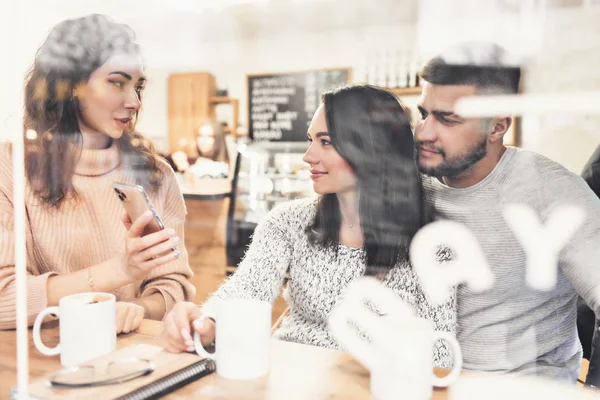 Un grupo de amigos que toman café o té juntos. Dos mujeres y dos hombres en un café, hablar, reír y disfrutar de su tiempo. Amistad con modelos de personas reales . — Foto de Stock