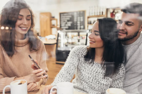 Un grupo de amigos que toman café o té juntos. Dos mujeres y dos hombres en un café, hablar, reír y disfrutar de su tiempo. Amistad con modelos de personas reales . — Foto de Stock