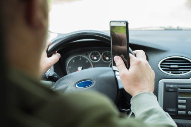 Araba kullanırken telefonu kullanan adam