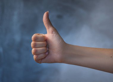 Female hand shows a sign that symbolizes like on a gray background.