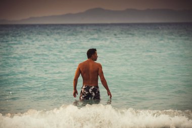 Kamuflaj şortlu, spor görünümlü bir adam. 