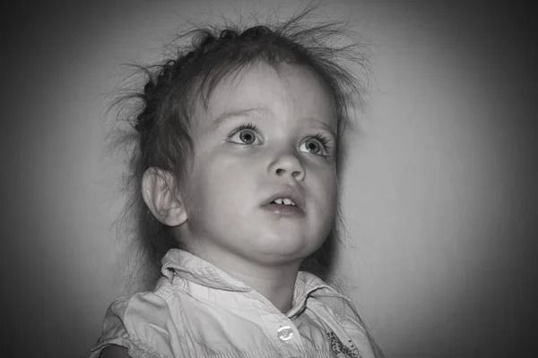 Little girl looking up with interest and fear on a black and white background