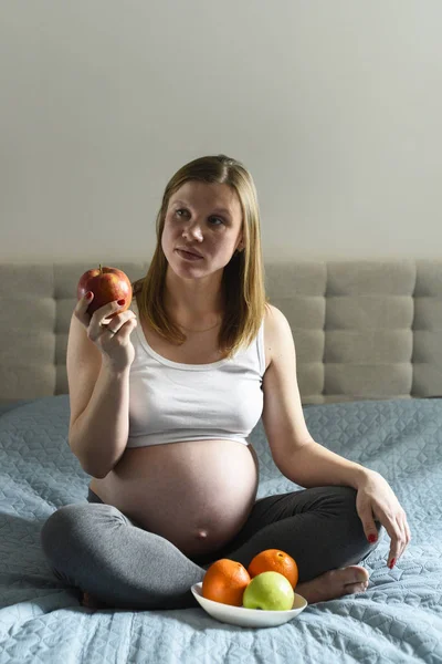 Proper nutrition during pregnancy. Vitamins and fruit. Pregnant women eating apple