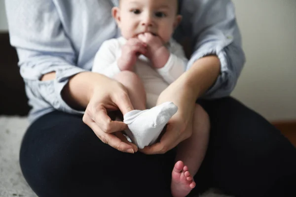 Joven madre pone los calcetines en su pequeño bebé —  Fotos de Stock