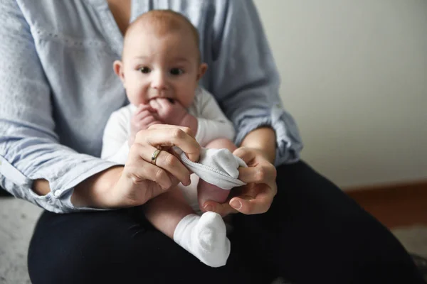 Joven madre pone los calcetines en su pequeño bebé —  Fotos de Stock