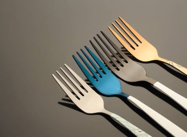 Siyah arka planda renkli metal çatallar, çatal bıçak takımı.