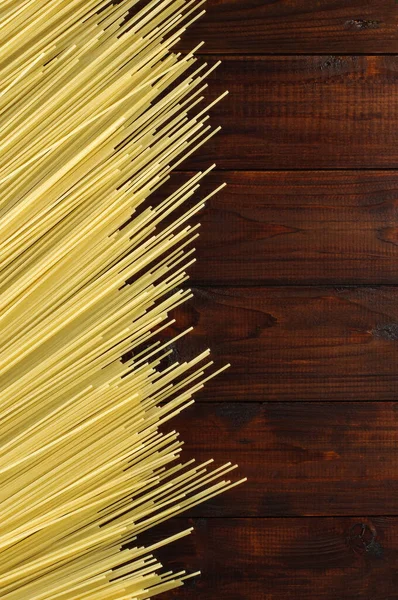 未煮熟的意大利面放在木制背景上 黄色意大利面 长意大利面 粮食背景概念 意大利食品和菜单概念 文本的复制空间 — 图库照片