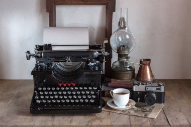 Natürmort ev iç ayrıntıları. Vintage retro gazeteci masaüstü fincan kahve, bakır sürahi, gaz lambası, kitap, gazete, rustik tarzı ahşap arka plan üzerinde typewrittert.