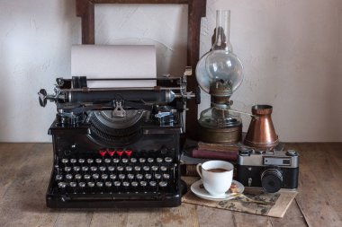 Eski retro gazeteci masaüstü fincan kahve, bakır sürahi, gaz lambası, kitap, gazete, ahşap rustik zemin üzerine typewritter ile.