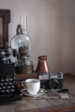 Natürmort ev iç ayrıntıları. Vintage retro gazeteci masaüstü fincan kahve, bakır sürahi, gaz lambası, kitap, gazete, rustik tarzı ahşap arka plan üzerinde typewrittert.