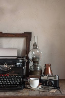 Natürmort ev iç ayrıntıları. Vintage retro gazeteci masaüstü fincan kahve, bakır sürahi, gaz lambası, kitap, gazete, rustik tarzı ahşap arka plan üzerinde typewrittert.