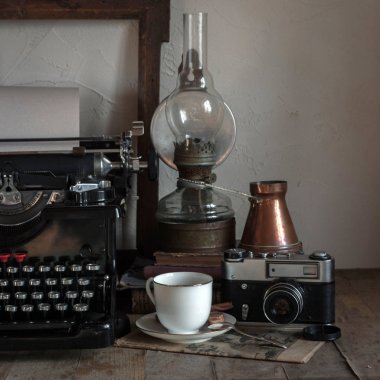 Natürmort ev iç ayrıntıları. Vintage retro gazeteci masaüstü fincan kahve, bakır sürahi, gaz lambası, kitap, gazete, rustik tarzı ahşap arka plan üzerinde typewrittert.